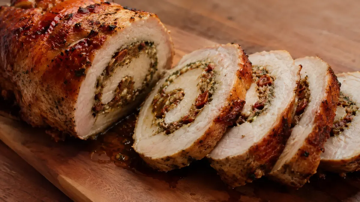 Carré de cerdo relleno cortado en rodajas que muestran el relleno en espiral