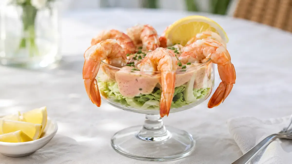 Copa de vidrio con cóctel de langostinos, salsa rosada y limón