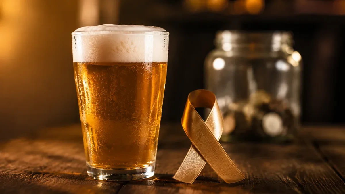 Vaso de cerveza artesanal junto a un lazo de tela como símbolo solidario, sobre una mesa de madera, sin personas